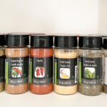 Various spice bottles, in a cupboard.
