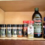 Various spice bottles, Olive oil and sesame seed oil in a cupboard.
