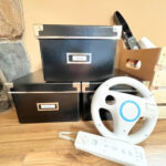 Three dark boxes with movies, games, and Wii video game accessories.